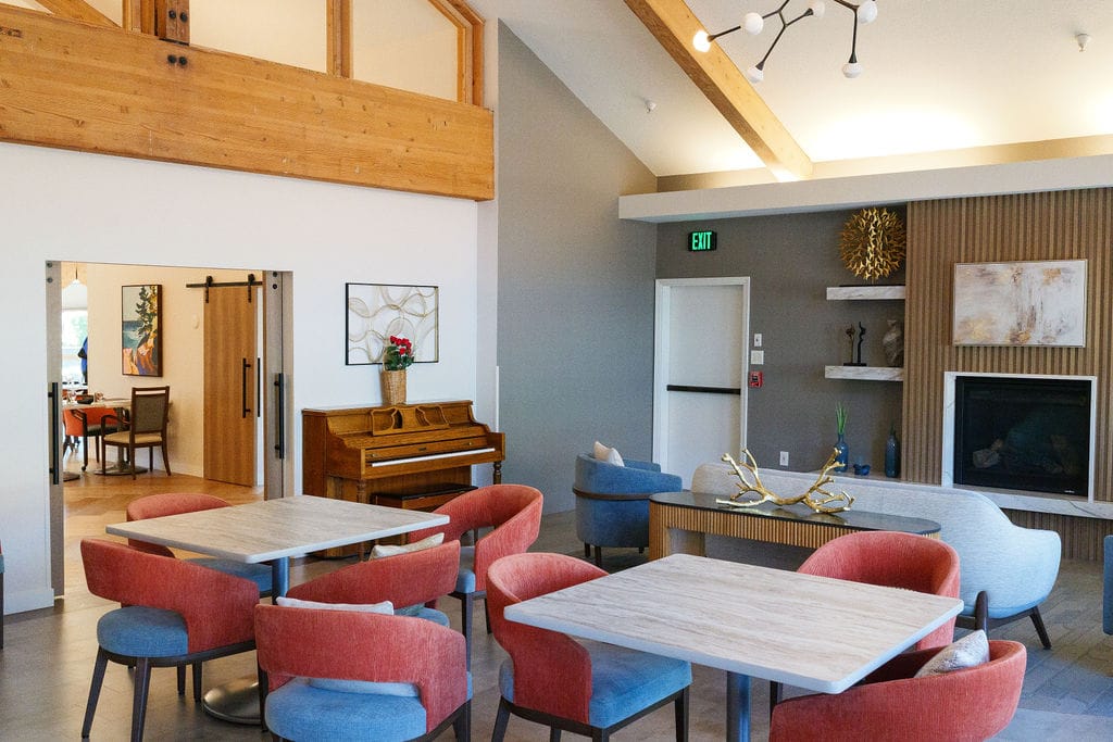 Bistro lounge at McLoughlin Place with an upright piano beside a fireplace and soft seating